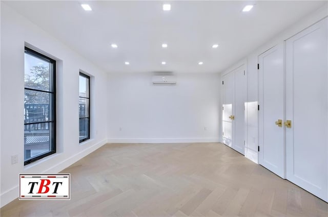 spare room featuring a wall mounted air conditioner and light parquet flooring