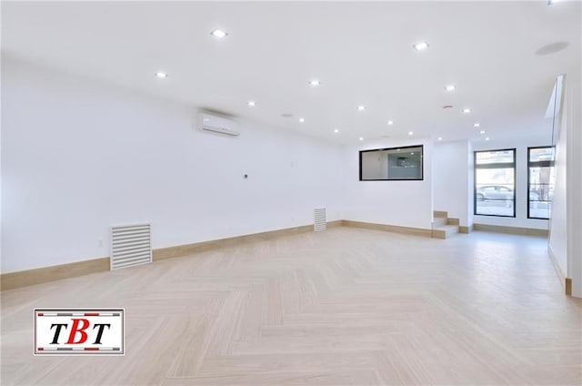 spare room featuring a wall unit AC and light parquet flooring