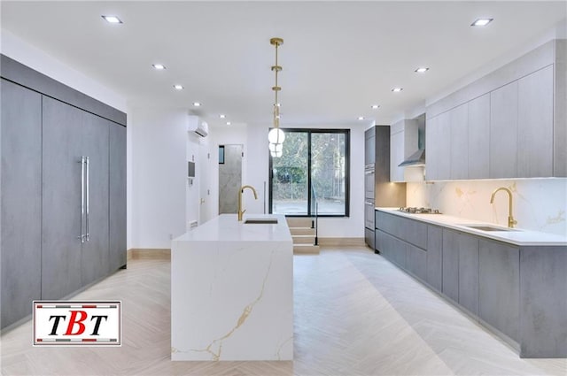 kitchen with gray cabinets, a large island, sink, and hanging light fixtures