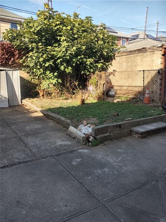view of yard with a storage shed, fence, an outbuilding, and a patio area