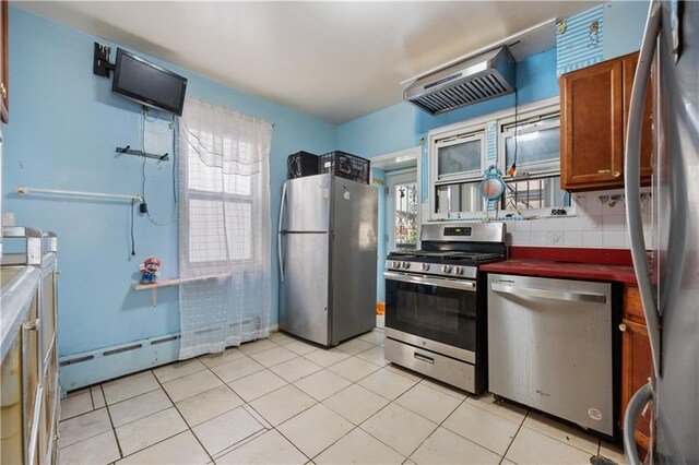 kitchen with backsplash, plenty of natural light, a baseboard radiator, and appliances with stainless steel finishes