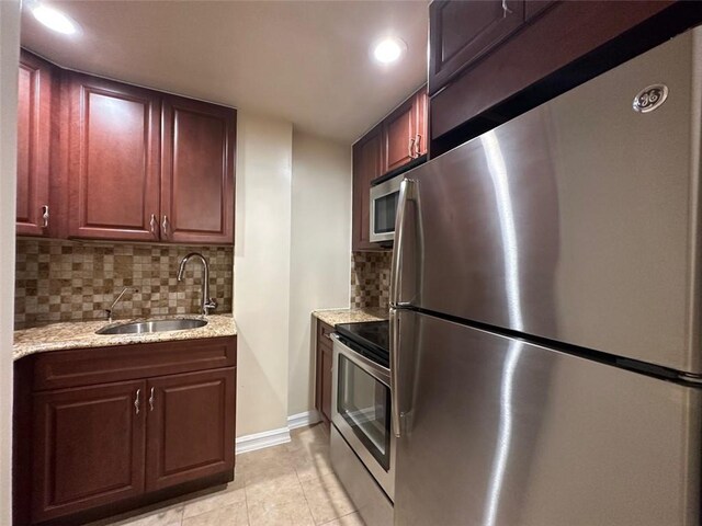 kitchen with tasteful backsplash, light stone counters, stainless steel appliances, sink, and light tile patterned floors