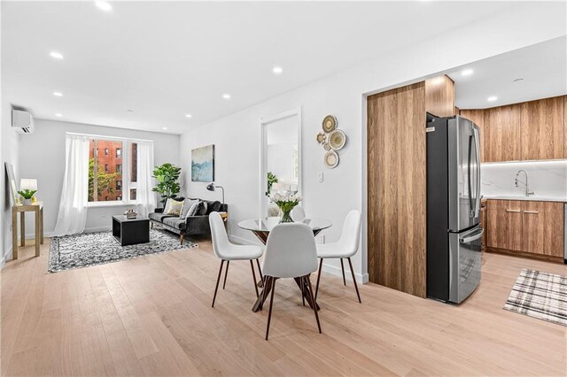 dining area with a wall mounted AC and light wood-type flooring