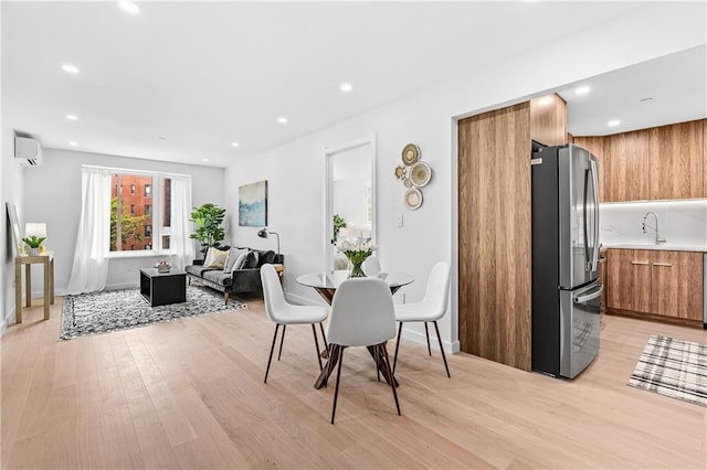 dining area featuring a wall mounted AC and light wood-type flooring