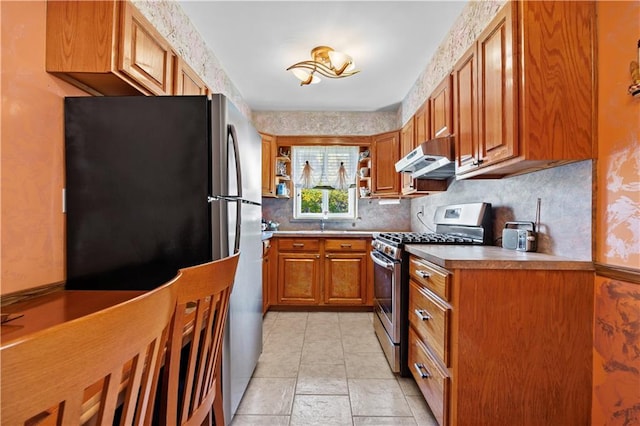 kitchen with open shelves, under cabinet range hood, appliances with stainless steel finishes, brown cabinets, and backsplash