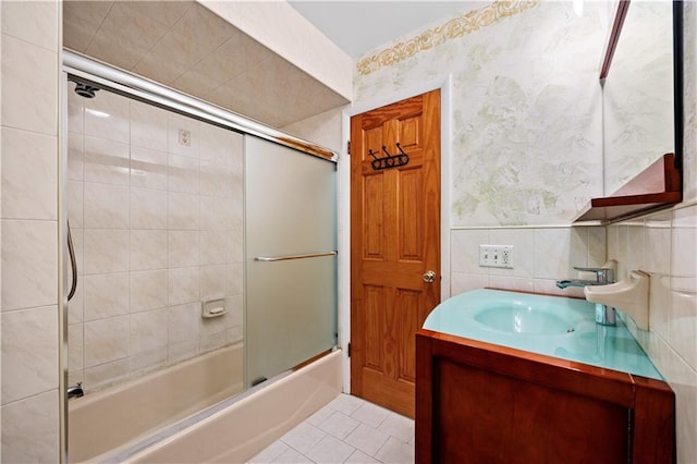 full bathroom featuring vanity, shower / bath combination with glass door, wallpapered walls, tile patterned floors, and tile walls