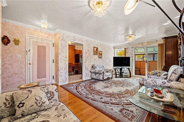 living area featuring light wood-type flooring, a textured ceiling, ornamental molding, and wallpapered walls