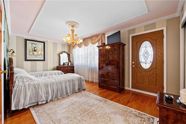 bedroom with ornamental molding, an inviting chandelier, and wood finished floors