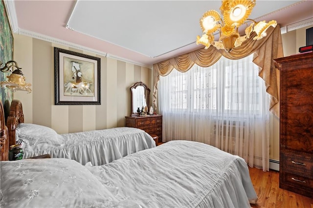 bedroom featuring a chandelier, baseboard heating, crown molding, and wood finished floors