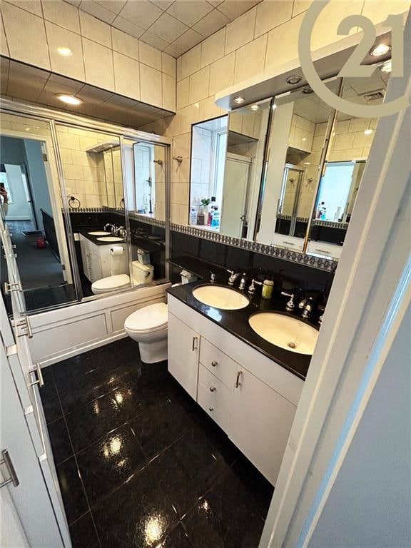 full bathroom with vanity, enclosed tub / shower combo, tile walls, and toilet