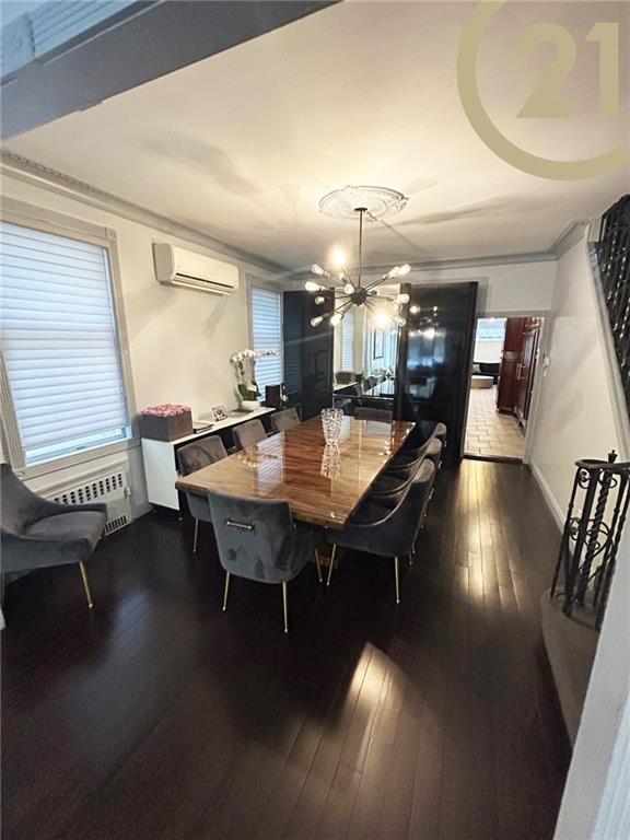 dining area with a wall mounted AC, an inviting chandelier, dark wood-type flooring, and ornamental molding