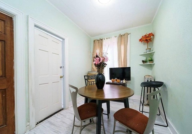 dining area with light wood-type flooring and crown molding