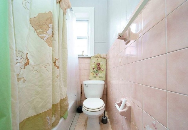 bathroom featuring tile patterned floors, tile walls, toilet, and shower / bath combination with curtain