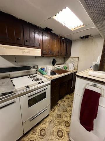 kitchen with ventilation hood, dark brown cabinets, and stove