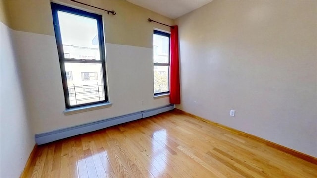 empty room with a baseboard heating unit and light hardwood / wood-style floors