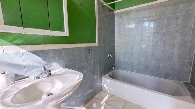 bathroom with tile patterned flooring, tiled shower / bath combo, sink, and tile walls