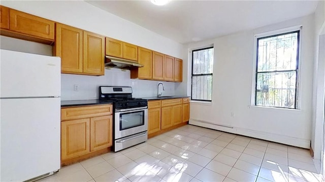 kitchen with light tile patterned flooring, sink, gas stove, white fridge, and a baseboard heating unit