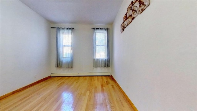 empty room featuring wood-type flooring and baseboard heating