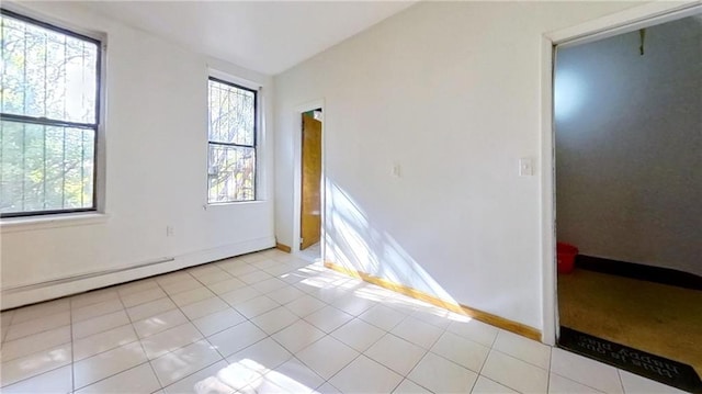 empty room with a baseboard heating unit and light tile patterned floors