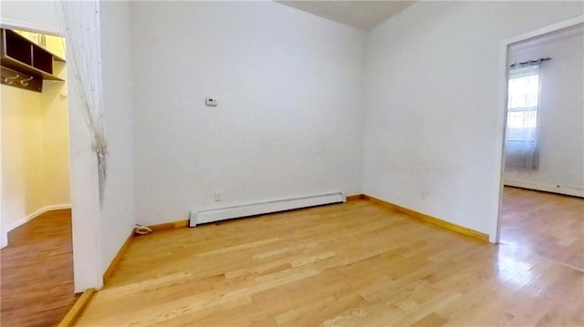 empty room featuring hardwood / wood-style floors and a baseboard heating unit