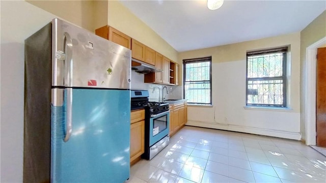 kitchen with sink, light tile patterned flooring, baseboard heating, and appliances with stainless steel finishes