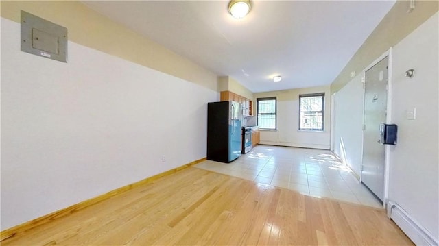 unfurnished room featuring a baseboard radiator, baseboards, and light wood finished floors