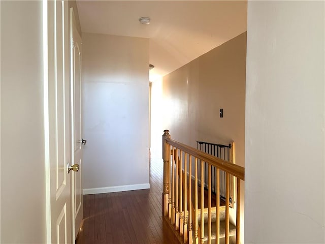 corridor with wood-type flooring, baseboards, and an upstairs landing