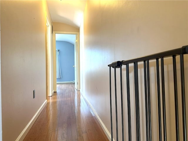 hall featuring lofted ceiling, dark wood-style floors, and baseboards