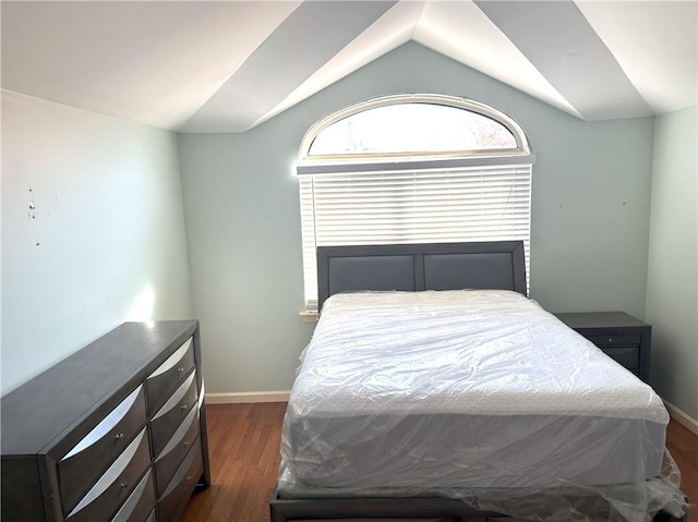 bedroom featuring lofted ceiling, baseboards, and dark wood finished floors