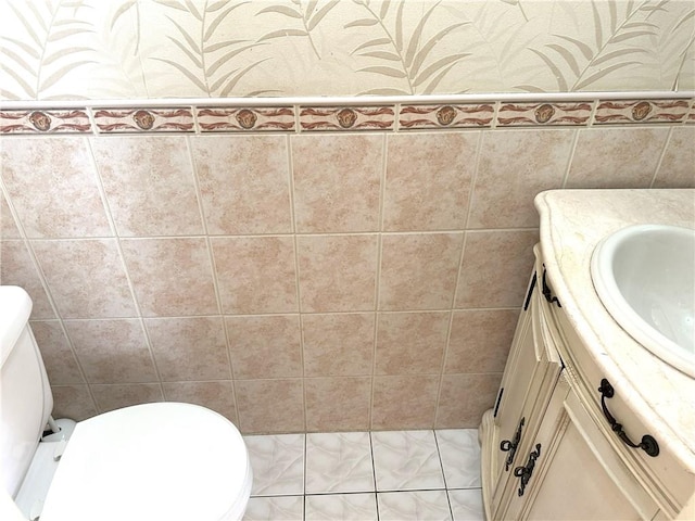 half bath with tile walls, vanity, and toilet