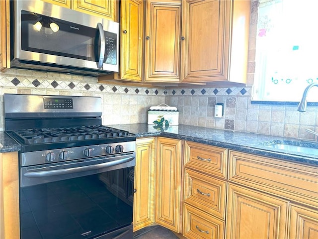 kitchen featuring stainless steel appliances, dark tile patterned flooring, backsplash, and a sink