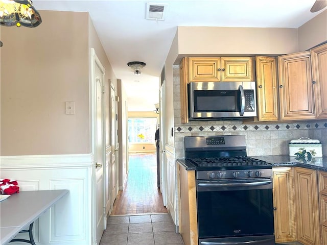 kitchen featuring tasteful backsplash, visible vents, dark countertops, stainless steel appliances, and light tile patterned flooring