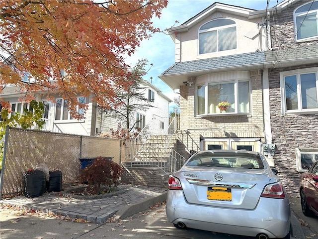 view of front of house featuring a shingled roof and fence