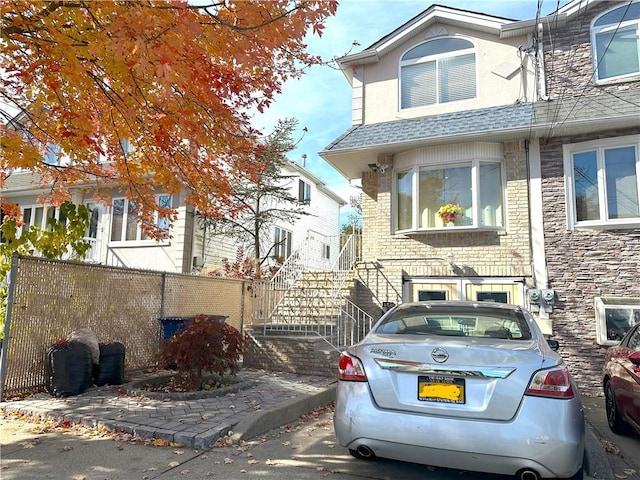 view of front of home with roof with shingles and fence