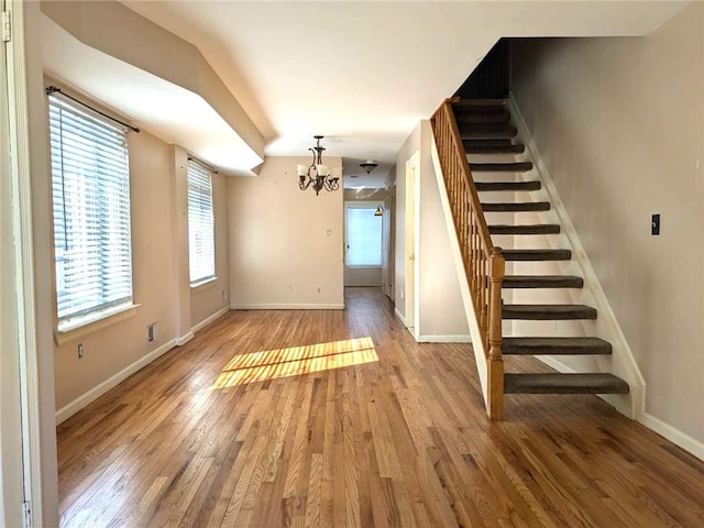 interior space with hardwood / wood-style flooring, baseboards, stairway, and a chandelier