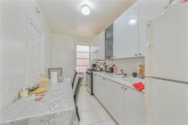 kitchen featuring white cabinetry, white appliances, backsplash, and light tile patterned floors