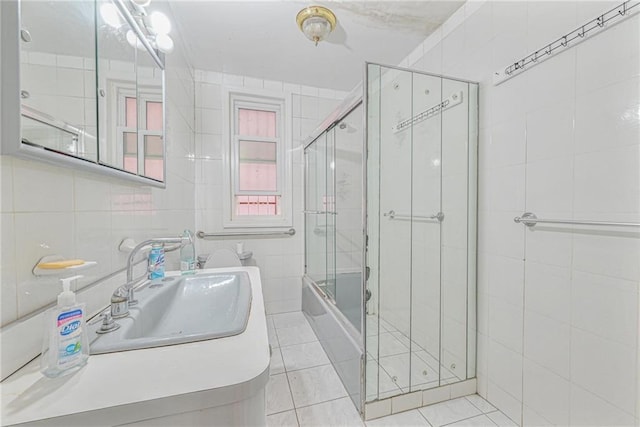 bathroom featuring tile patterned flooring, tile walls, vanity, and enclosed tub / shower combo