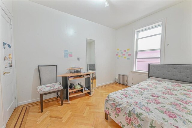 bedroom with radiator heating unit and light parquet floors