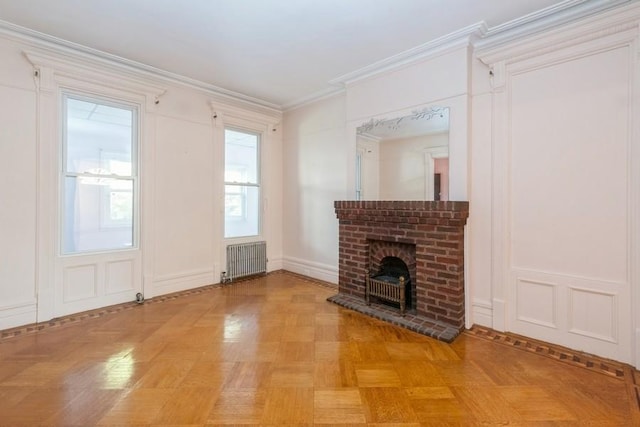 unfurnished living room with radiator, plenty of natural light, light parquet floors, crown molding, and a brick fireplace