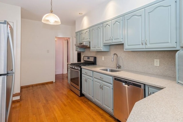 kitchen featuring sink, hanging light fixtures, light wood-type flooring, stainless steel appliances, and backsplash