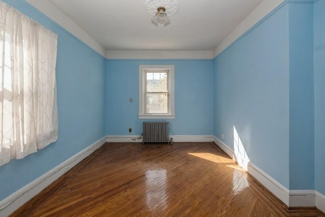 unfurnished room featuring wood-type flooring and radiator