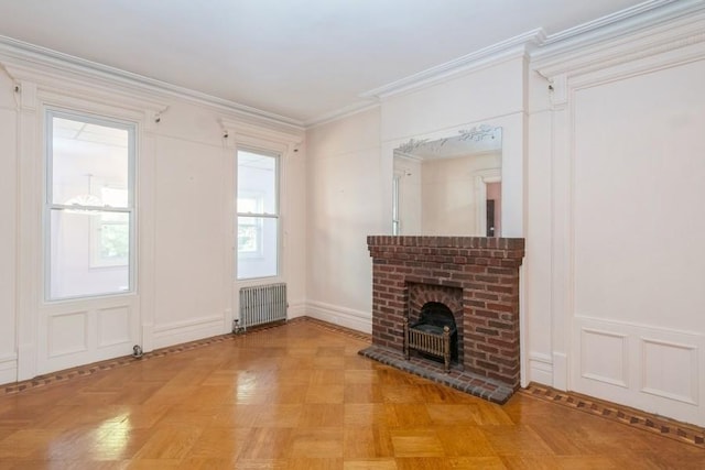 unfurnished living room featuring crown molding, light parquet flooring, radiator, and a brick fireplace