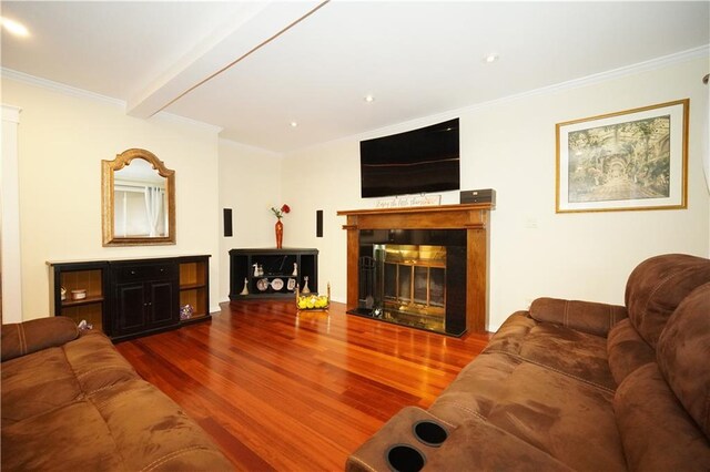 living room featuring wood-type flooring, ornamental molding, and beamed ceiling