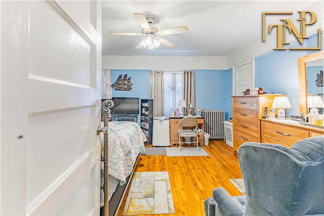 bedroom featuring ceiling fan, radiator heating unit, and light hardwood / wood-style flooring