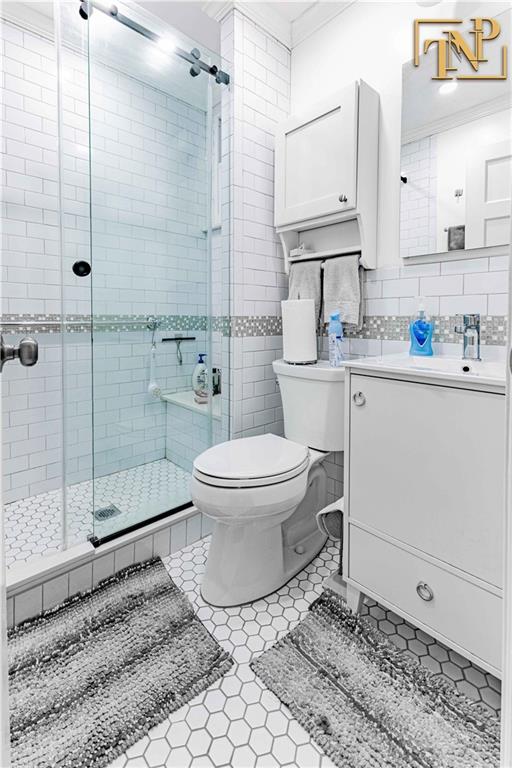 full bathroom featuring crown molding, a shower stall, vanity, tile patterned floors, and toilet