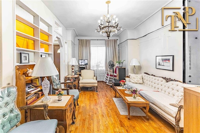 living room with an inviting chandelier, ornamental molding, and wood finished floors