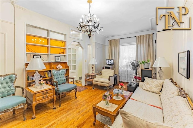 living area with arched walkways, a notable chandelier, and wood finished floors