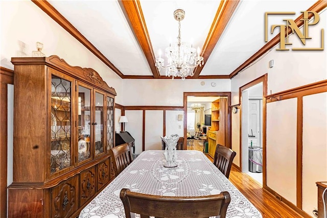 dining area with crown molding, beamed ceiling, an inviting chandelier, and hardwood / wood-style flooring