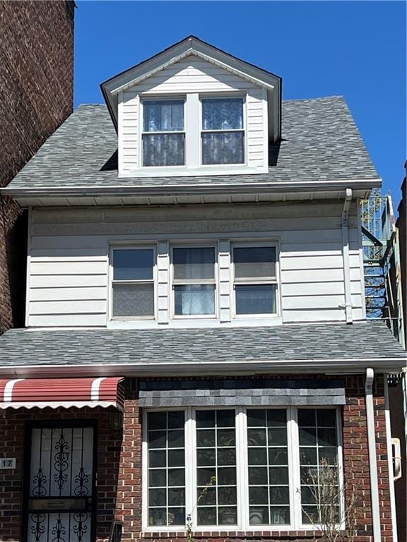 view of side of home with a shingled roof and brick siding