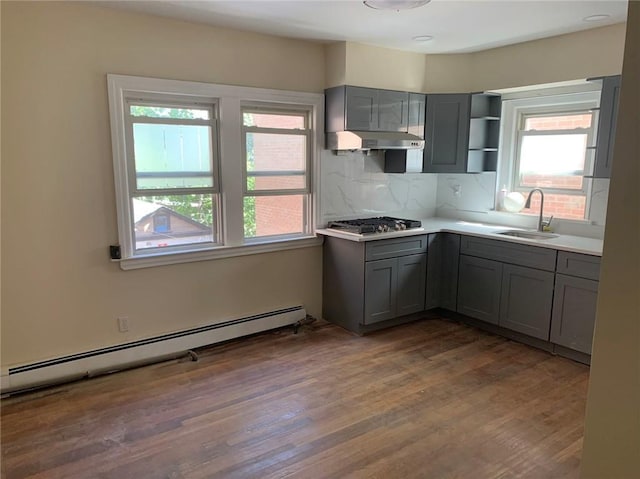 kitchen featuring stainless steel gas stovetop, sink, dark hardwood / wood-style floors, gray cabinets, and a baseboard radiator